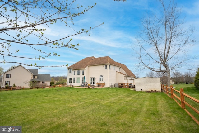 rear view of house with fence, an outdoor structure, and a yard