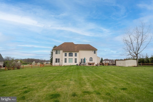 rear view of house featuring fence and a yard