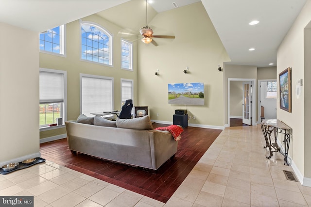 living area with tile patterned flooring, a ceiling fan, visible vents, and baseboards