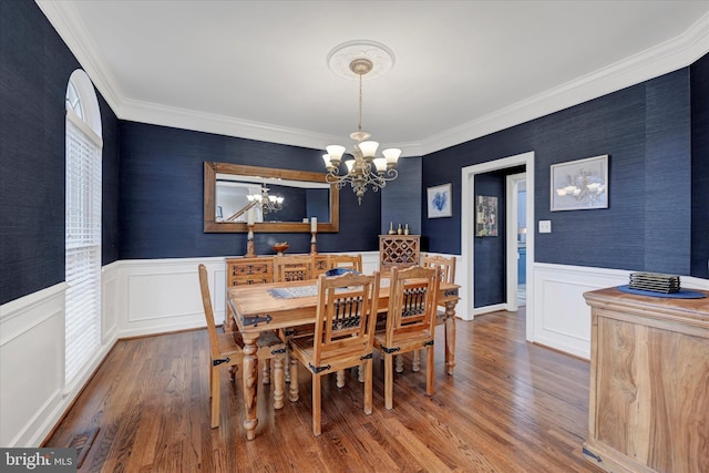 dining room with wainscoting, wood finished floors, an inviting chandelier, and crown molding