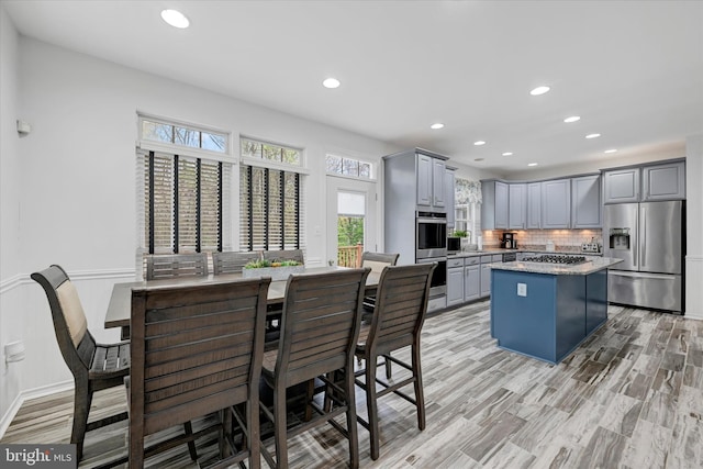 kitchen featuring decorative backsplash, gray cabinetry, stainless steel appliances, a center island, and recessed lighting
