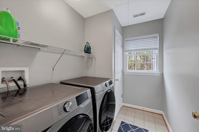 laundry room featuring washing machine and clothes dryer, light tile patterned floors, laundry area, visible vents, and baseboards