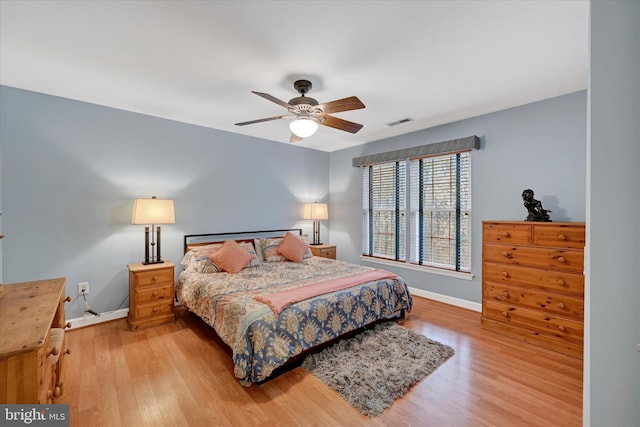 bedroom with baseboards, visible vents, wood finished floors, and a ceiling fan