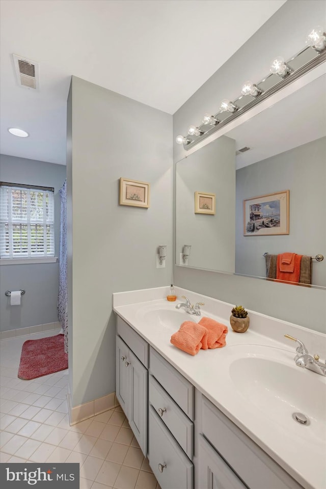 full bath featuring tile patterned floors, visible vents, double vanity, and a sink