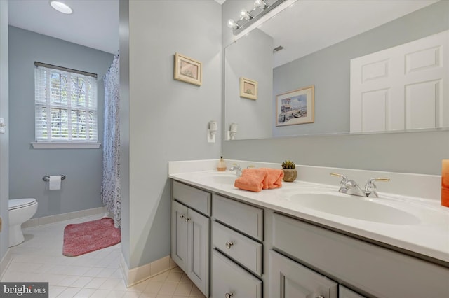 bathroom featuring double vanity, toilet, tile patterned floors, and a sink