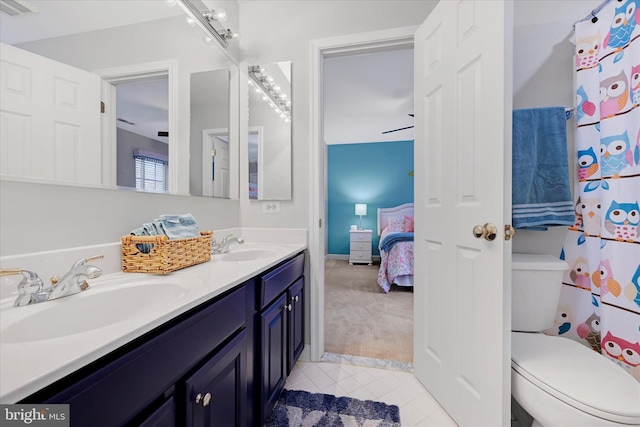 full bath with toilet, double vanity, a sink, and tile patterned floors