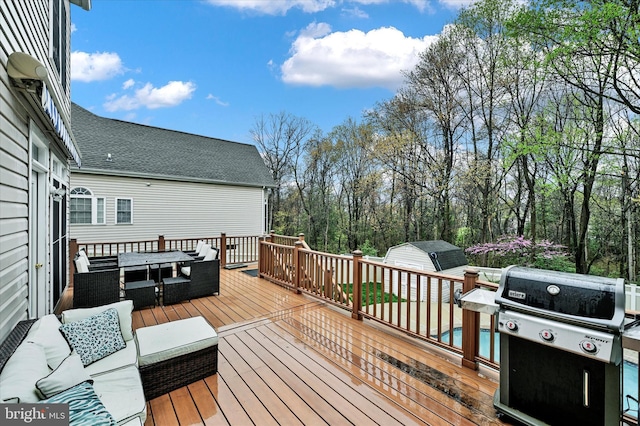 wooden terrace featuring an outdoor structure, a shed, outdoor dining area, and grilling area