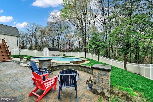 view of patio / terrace with a fire pit, a fenced in pool, an outbuilding, a storage shed, and a fenced backyard