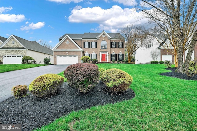 colonial home featuring brick siding, driveway, an attached garage, and a front yard