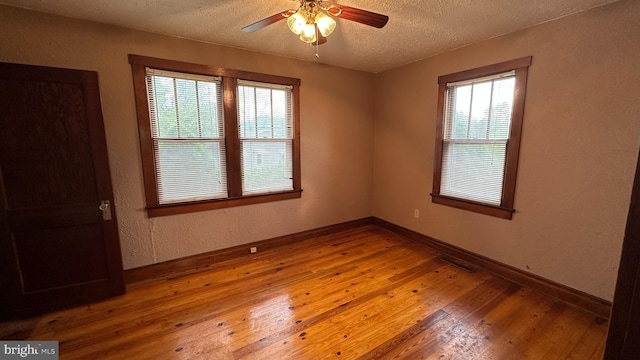 unfurnished room with baseboards, hardwood / wood-style flooring, ceiling fan, and a textured ceiling