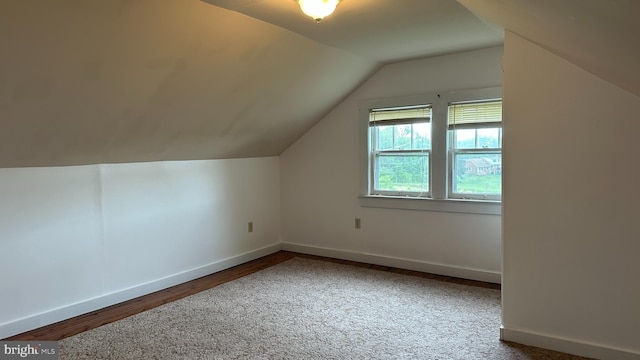 additional living space with vaulted ceiling, wood finished floors, and baseboards