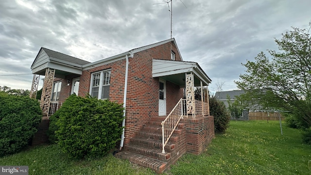 view of home's exterior featuring brick siding, fence, and a yard