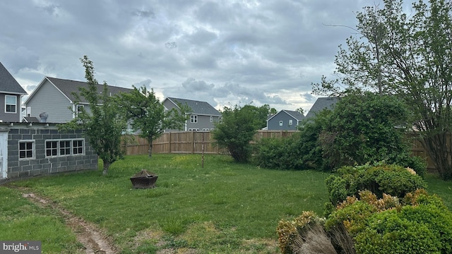 view of yard featuring a residential view, a fire pit, and a fenced backyard