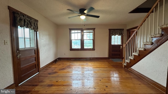foyer with hardwood / wood-style floors, stairs, and a textured wall