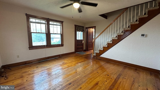 foyer featuring stairway, baseboards, a textured ceiling, and wood-type flooring