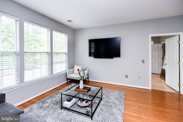living room featuring plenty of natural light, light wood finished floors, baseboards, and visible vents