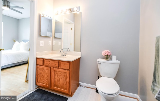 bathroom with baseboards, connected bathroom, toilet, and vanity
