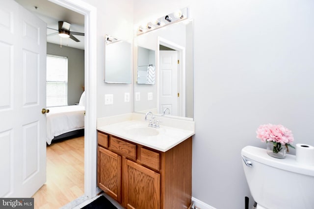 ensuite bathroom with connected bathroom, vanity, toilet, a ceiling fan, and wood finished floors