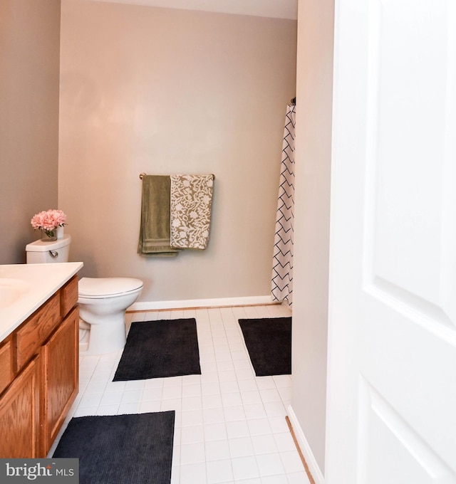 bathroom featuring tile patterned flooring, vanity, curtained shower, toilet, and baseboards