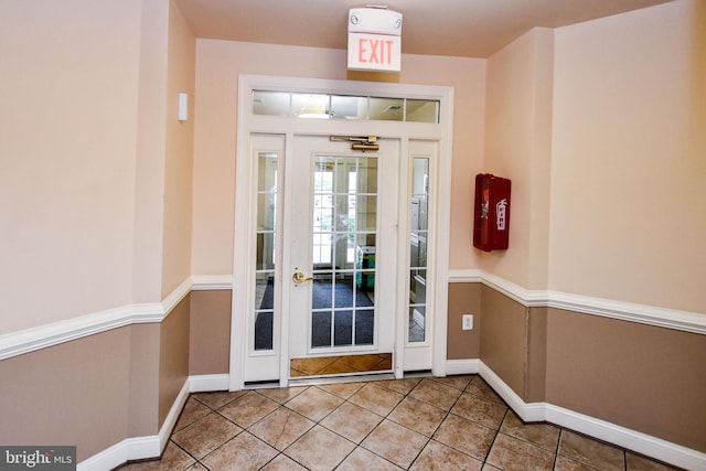 doorway with tile patterned floors and baseboards