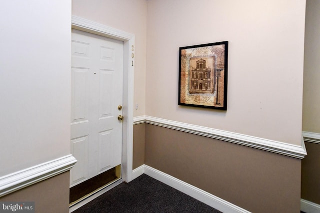 doorway with baseboards and dark carpet