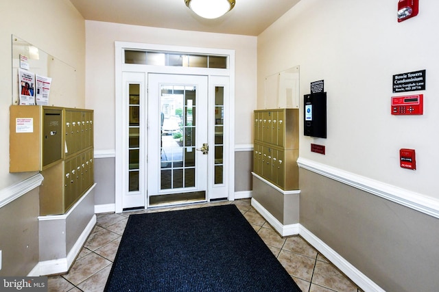 doorway to outside featuring baseboards, tile patterned flooring, and mail area