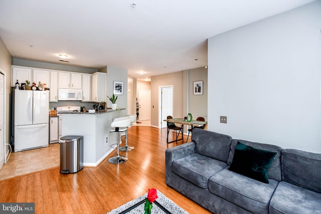 living area featuring light wood-style floors and baseboards