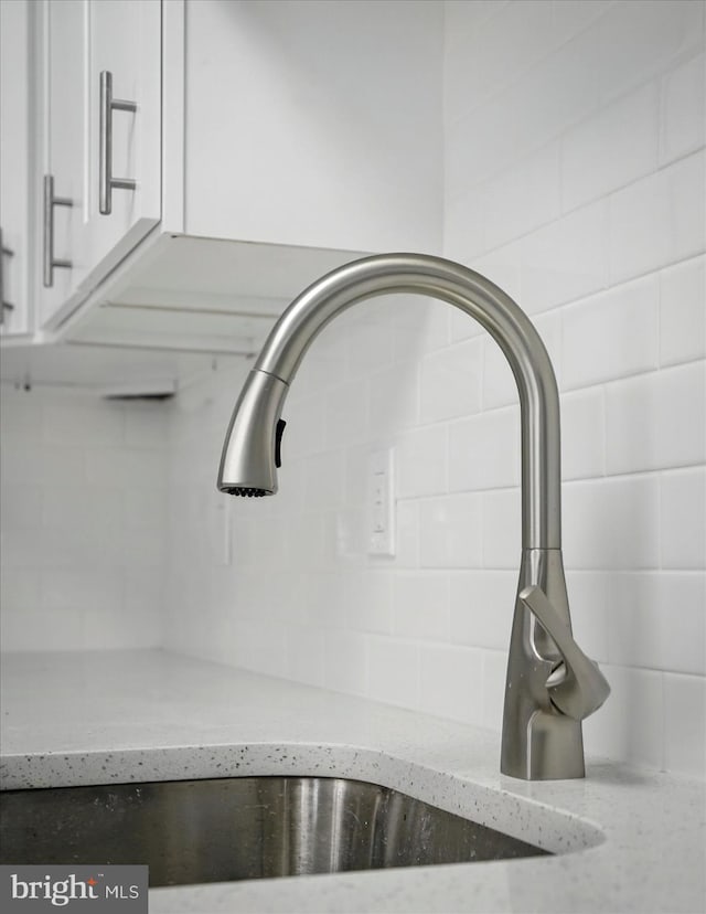 1212 Primrose Ave, Baltimore, MD 21237 - interior details with light stone countertops, a sink, white cabinets, and backsplash