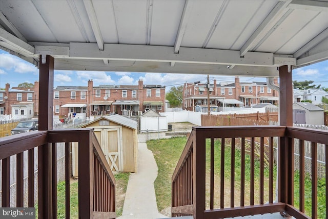 1212 Primrose Ave, Baltimore, MD 21237 - deck featuring an outdoor structure, a fenced backyard, a residential view, a shed, and a lawn