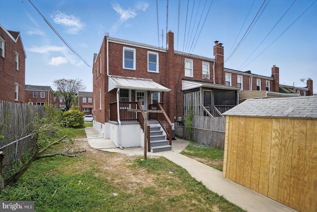 1212 Primrose Ave, Baltimore, MD 21237 - back of property with a storage unit, an outbuilding, fence, brick siding, and a sunroom