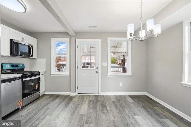 1212 Primrose Ave, Baltimore, MD 21237 - kitchen with white cabinets, stainless steel appliances, baseboards, an inviting chandelier, and light wood-type flooring
