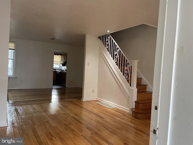 stairs with wood finished floors, visible vents, and baseboards