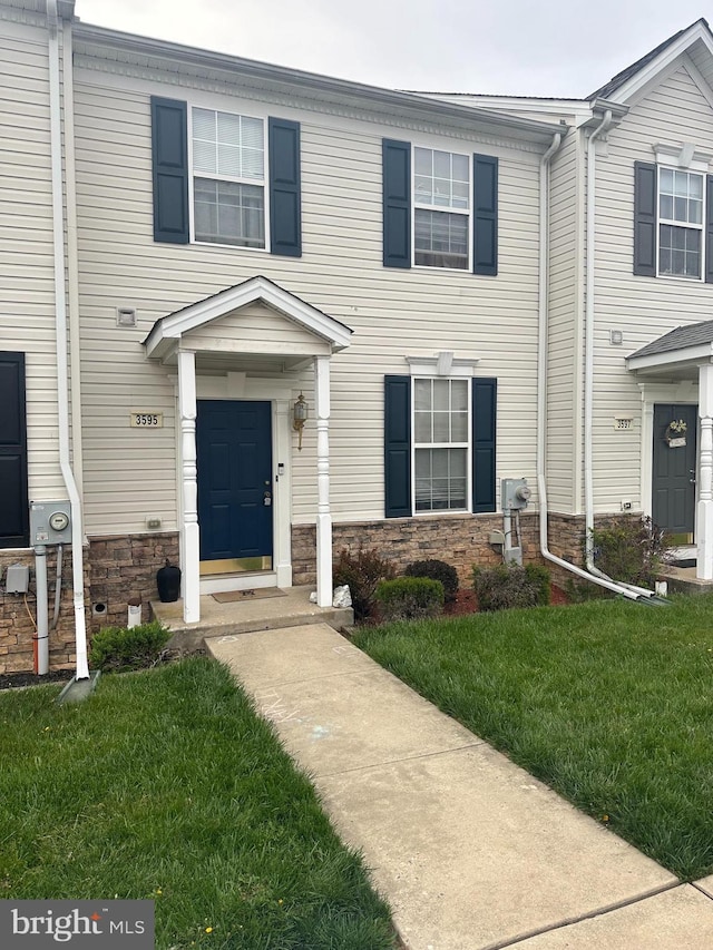 multi unit property featuring a front yard and stone siding