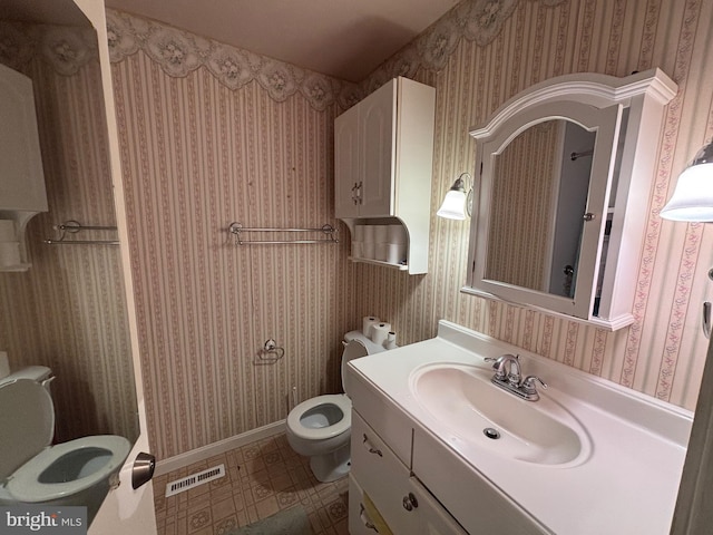 bathroom featuring baseboards, visible vents, toilet, and vanity