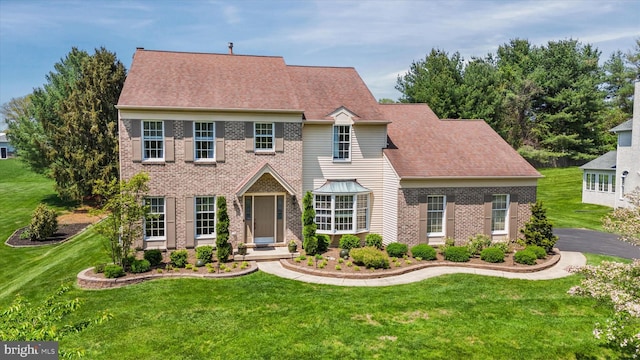 colonial home featuring brick siding and a front lawn