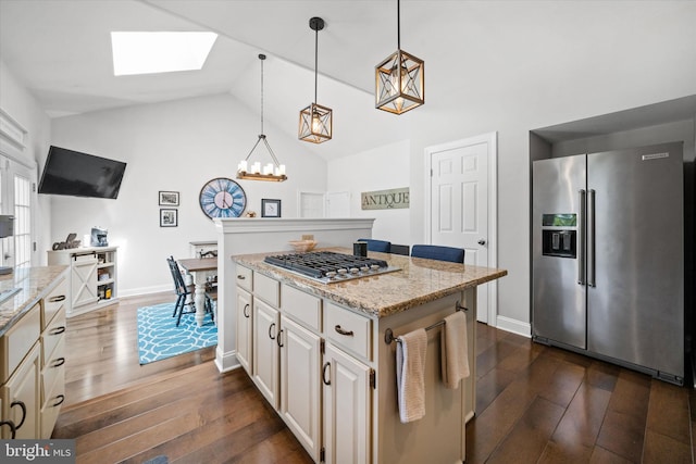 kitchen featuring appliances with stainless steel finishes, a center island, dark wood-style floors, and light stone counters