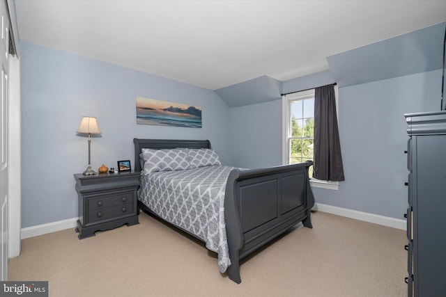 bedroom with baseboards, lofted ceiling, and light colored carpet
