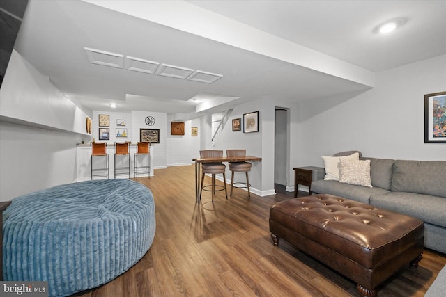 living area with baseboards, bar, and wood finished floors