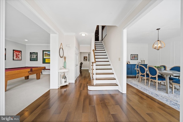foyer featuring billiards, crown molding, a chandelier, stairs, and hardwood / wood-style floors