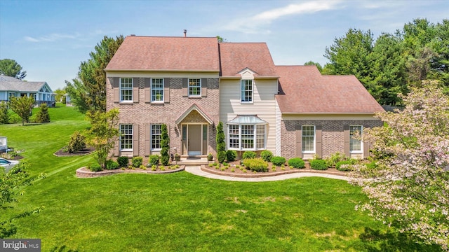 colonial home featuring brick siding and a front lawn
