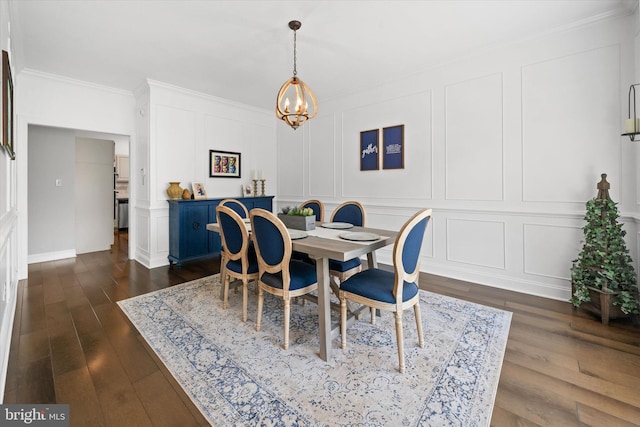 dining room with dark wood-style flooring, crown molding, baseboards, a chandelier, and a decorative wall
