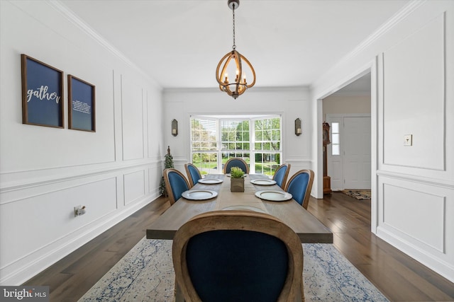 dining room featuring ornamental molding, a decorative wall, a notable chandelier, and dark wood-style floors
