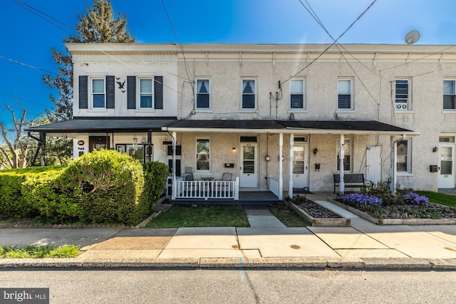 townhome / multi-family property with stucco siding and a porch