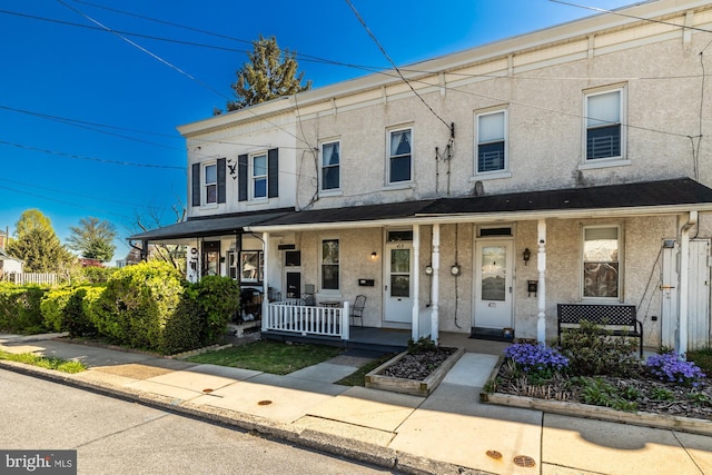 townhome / multi-family property featuring a porch and stucco siding