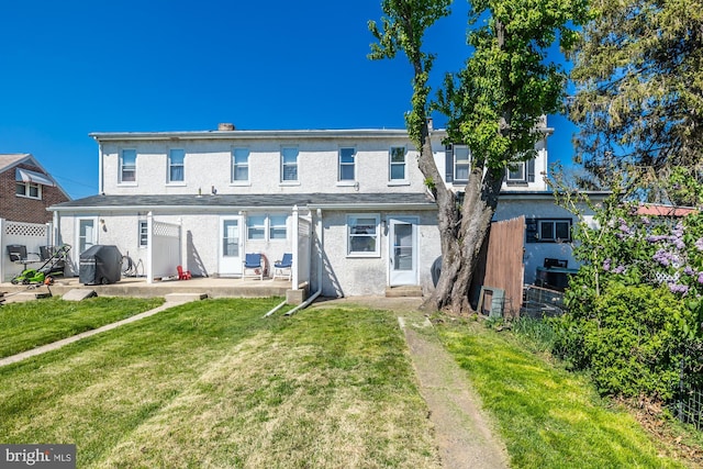 rear view of property with a lawn, a patio, fence, and stucco siding