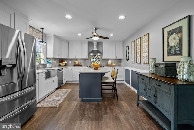 kitchen featuring appliances with stainless steel finishes, a sink, wall chimney exhaust hood, a ceiling fan, and recessed lighting