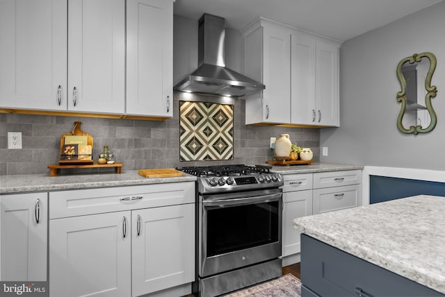 kitchen with tasteful backsplash, stainless steel range with gas cooktop, wall chimney exhaust hood, and white cabinetry