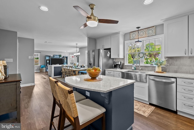 kitchen with ceiling fan with notable chandelier, a sink, dark wood finished floors, appliances with stainless steel finishes, and backsplash
