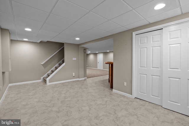 finished below grade area featuring stairway, baseboards, recessed lighting, and a paneled ceiling