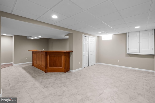basement with baseboards, a bar, a drop ceiling, and recessed lighting